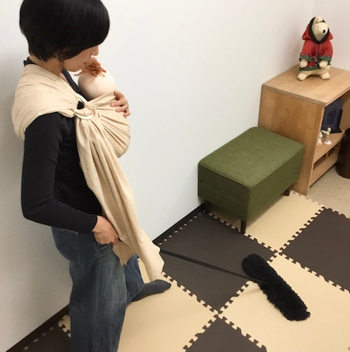 スリングで赤ちゃんを抱っこして掃除をする女性